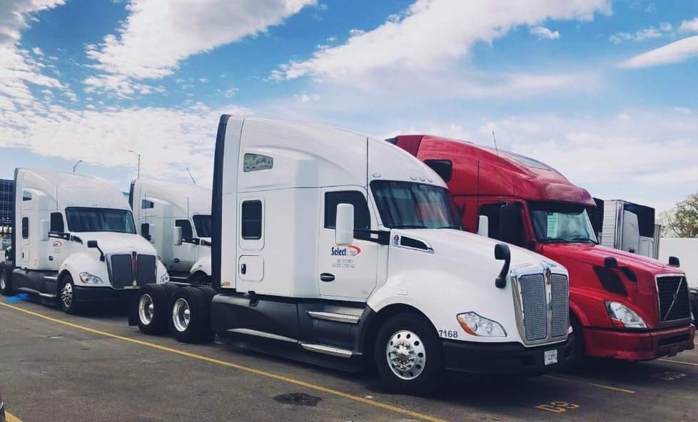 A white semi truck parked next to another red truck.