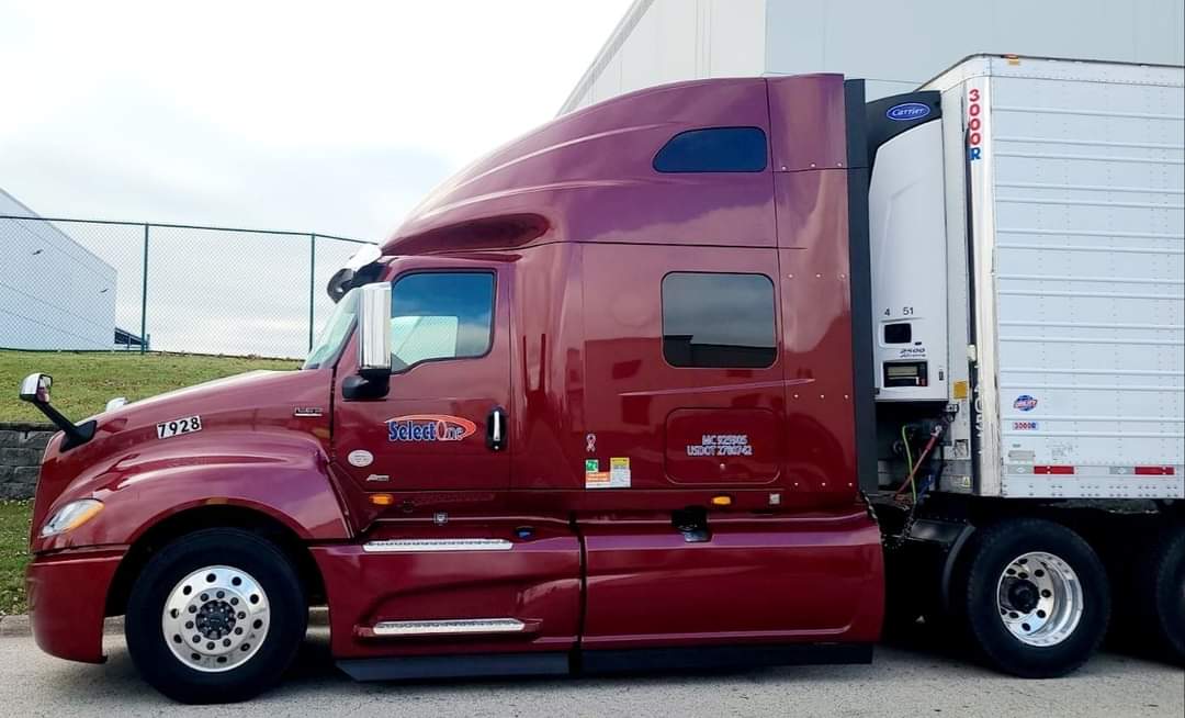 A red semi truck parked in front of a building.